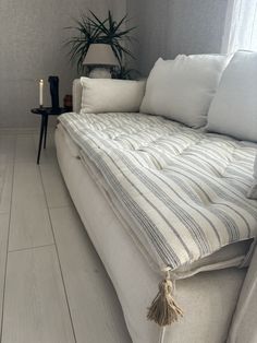 a living room with a white couch and some pillows on the floor next to a table