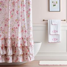 a bathroom with pink walls and floral shower curtain