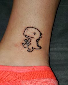 a small tattoo on the ankle of a woman's foot with a dinosaur holding a flower