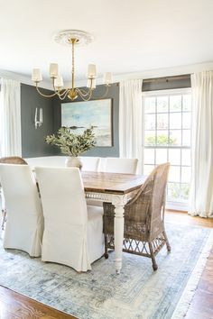 a dining room table with white chairs and a chandelier