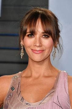 a close up of a person wearing a dress and smiling with her hair in a bun