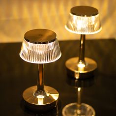 two lamps sitting on top of a table next to each other with dim lights in them