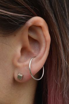 a close up of a person's ear wearing a pair of silver hoop earrings