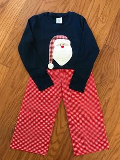 This precious little outfit is perfect for photos with Santa or Christmas celebrations.  This outfit includes a navy blue cotton t-shirt (available in long or short sleeve) with an applique of Santa on the chest.  This is available with or without your child's name underneath.  It also includes a pair of adorable red gingham pants.   Please include in the notes at checkout your child's name if you would like the shirt personalized. Baby Doll Diaper Bag, Photos With Santa, Personalized Dolls, Gingham Pants, Santa Outfit, Saint Marys, Little Outfits, Red Gingham, Clothing Sets