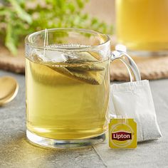 a glass cup filled with green tea next to a spoon and napkin on a table