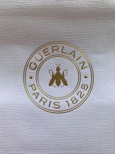 the logo for guberian paris 1876 on a white cloth with gold foiling