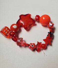 a bracelet made out of red glass beads and other items on a white table top