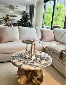 a living room filled with furniture and a christmas tree in the window sill behind it