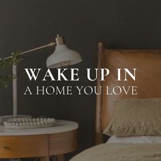 a bed sitting next to a table with a lamp on top of it and the words wake up in a home you love