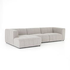 a large sectional sofa sitting on top of a white floor next to an ottoman chair