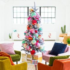 a brightly colored christmas tree in the middle of a living room with colorful chairs around it