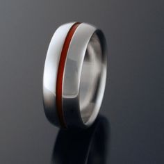 a wedding ring with red and white stripes on the inside is seen against a black background