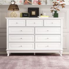 a white dresser with many drawers and pictures on the wall