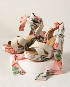 a pair of white high heeled sandals with floral print