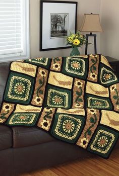 a couch with a green and yellow quilt on it next to a framed photo in a living room