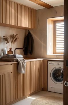 a washer sitting next to a window in a room with wood paneling on the walls