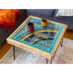 a coffee table with a blue design on the top and two cups sitting on it