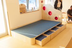 two people are standing in the corner of a room with a blue carpet and stairs