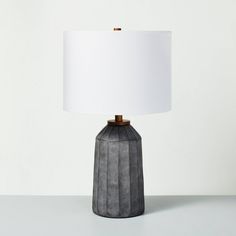 a gray table lamp with a white shade on it