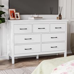 a flat screen tv sitting on top of a white dresser