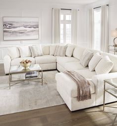 a living room filled with furniture and a large white sectional couch in front of a window