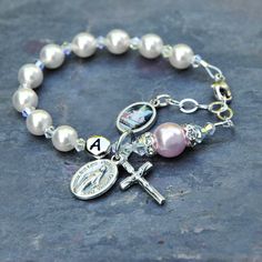 Celebrate the Baptism of a baby girl with this beautiful white and rosaline pink guardian angel rosary bracelet. The bracelet features genuine Swarovski crystals and crystal pearls throughout. The bracelet has white Swarovski pearls for the Hail Mary prayers and just a touch of rosaline pink with the larger Our Father pearl. In between are sparkly Swarovski crystals with an aurora borealis finish. The Our Father pearl is surrounded by crystal rhinestone rondelles. If you select the personalizati Personalized Silver Rosary Bracelet For Confirmation, Personalized Adjustable Rosary Bracelet For Confirmation, Personalized White Pearl Bracelet For Baptism, White Jewelry For Confirmation On Mother's Day, Personalized Spiritual Bracelets For First Communion, Personalized Pink Spiritual Charm Bracelet, Pink Spiritual Jewelry For First Communion, Personalized White Rosary Bracelet For Baptism, White Miraculous Medal Jewelry For First Communion