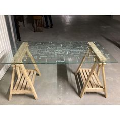 two wooden chairs sitting next to each other in front of a glass table with writing on it