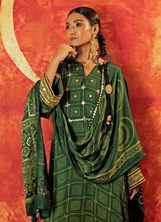 Embrace elegance with the Green Embroidered and Hand-Blocked Satin Kurta Pant Set, a seamless fusion of tradition and modern style. Crafted from luxurious satin silk, the rich green kurta is adorned with intricate hand embroidery, featuring gold sequins, zari, and pitta work on the yoke and sleeves, accented by mirror-like sequins for a subtle sparkle. Paired with comfortable straight-leg pants made from vegan satin, this set offers both style and ease. Completed with an ajrakh dupatta, beautifully hand-embroidered with geometric patterns, adding a sophisticated touch. An ideal Kurta Set for festive occasions, family gatherings, or home poojas. Composition : Top - Handblocked Satin Silk, Bottom - Satin and Dupatta - Ajrakh Satin Care: Dry Clean Only and Vacuum Storage This product can be c Pitta Work, Ajrakh Dupatta, Satin Kurta, Kurta Pant Set, Vacuum Storage, Indian Wedding Wear, Rich Green, Kurta With Pants, Gold Sequins