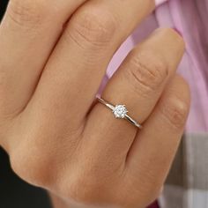 a woman's hand with a diamond ring on top of her finger, showing the side view