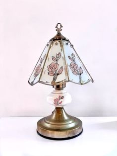 a lamp that is sitting on top of a white table with a rose design on it