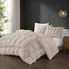 a white comforter on a bed in a room with dark walls and wood flooring