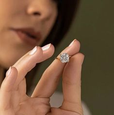 a close up of a person holding a ring with a diamond in it's middle