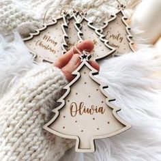 two wooden christmas tree ornament hanging on a white furnishing with the word ohana in gold lettering