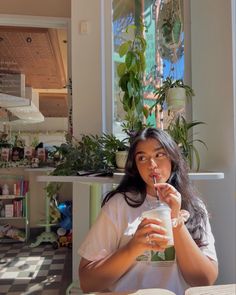 a woman sitting at a table with a drink in her hand