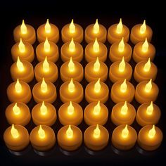 several rows of lit candles in the dark