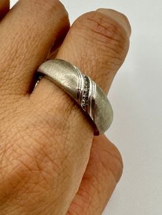 A refined vintage wedding band. If you are on the hunt for the ring that will grace your hand forever, look no further! This timeless piece is in sterling silver with a row of diamonds. Balancing masculine and romantic. Marked: P4SR Jewelry Measurements: Ring Size: 12.5 Condition: AB. See the Condition Grade Scale on the photo carousel. Damage to consider: See images Care: Clean with a sunshine cloth, use warm water and dish soap when necessary for a deeper clean. Disclaimer: Vintage items are u Classic Silver Rings With Diamond Accents, Classic Silver Diamond Band, Classic Sterling Silver Promise Bands, Classic Bands With Single Cut Diamonds For Promise Ring, Silver Brilliant Cut Bands For Promise Ring, Classic Bands With Diamond Accents For Promise Ring, Classic Promise Bands With Diamond Accents, Vintage Promise Rings With Polished Finish, Silver Promise Ring With Half Eternity Detail