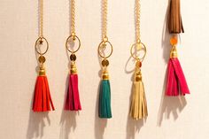 five tassels hanging from gold chains on a white wall, one with a keychain