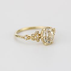 a yellow gold engagement ring with an oval cut diamond in the center and two smaller round diamonds on each side