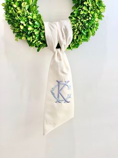 a wreath with a monogrammed k on it hanging from the side of a wall