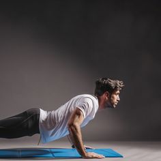 a man is doing push ups on a blue mat in the middle of his body