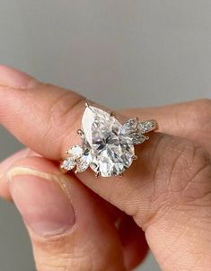 a woman's hand holding an engagement ring with three stones on the top and bottom