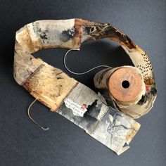 an old pair of scissors and some fabric on a black surface with a spool of thread next to it