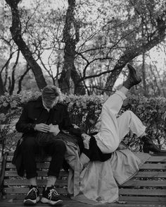 two people sitting on a bench in the park