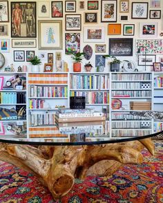 a glass table with books on it in front of a wall full of pictures