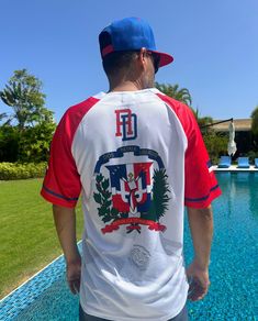 TAINOWEARS Dominicana Baseball Jersey in Classic White. This Dominican Republic baseball jersey features vibrant 'Dominicana' embroidery on the front, the national coat of arms on the back, and the iconic Dominican flag and map on the sleeves. Whether you're cheering on your team at a game or attending a casual event, this jersey is the perfect way to showcase your pride and patriotism. White Baseball Jersey, Dominican Flag, Dominican Republic Flag, Vibrant Style, Patriotic Outfit, Baseball Jersey, Baseball Jerseys, Dominican Republic, Coat Of Arms