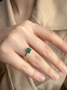 a woman's hand with a green ring on her left hand and an emerald stone in the middle