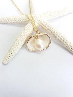 Beautiful gold sea shell necklace made with a gold plated seashell charm with a gold filled chain and fresh water pearl. This necklace makes a unique gift for a beach lover or someone special in your life. The seashell is around 15- 20mm long. Each item is carefully packaged in a beautiful jewellery box ready as a gift. If you would like to add a personalized note with your order, just write a note at checkout and I will send a small card with your gift to the recipient. Please choose necklace l Handmade Gold Shell Strand, Handmade Gold Strand Shell, Gold Strand Charm Necklace For Gift, Gold Strand Charm Necklace As Gift, Gold Strand Jewelry For Gift, Beach Shell-shaped Charm Necklaces With Pearl, Shell-shaped Pearl Charm Necklaces For Beach, Shell-shaped Charm Necklaces With Pearl Charm For Beach, White Shell Charm Necklace Gift