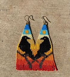 a pair of earrings made out of seed beads with an eagle on the front and side