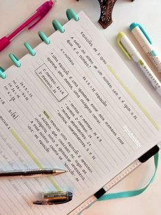 several pens and pencils are sitting on top of a paper with writing utensils next to it