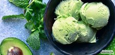 three scoops of green ice cream in a bowl next to an avocado